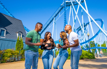 Four people in front of a roller coaster
